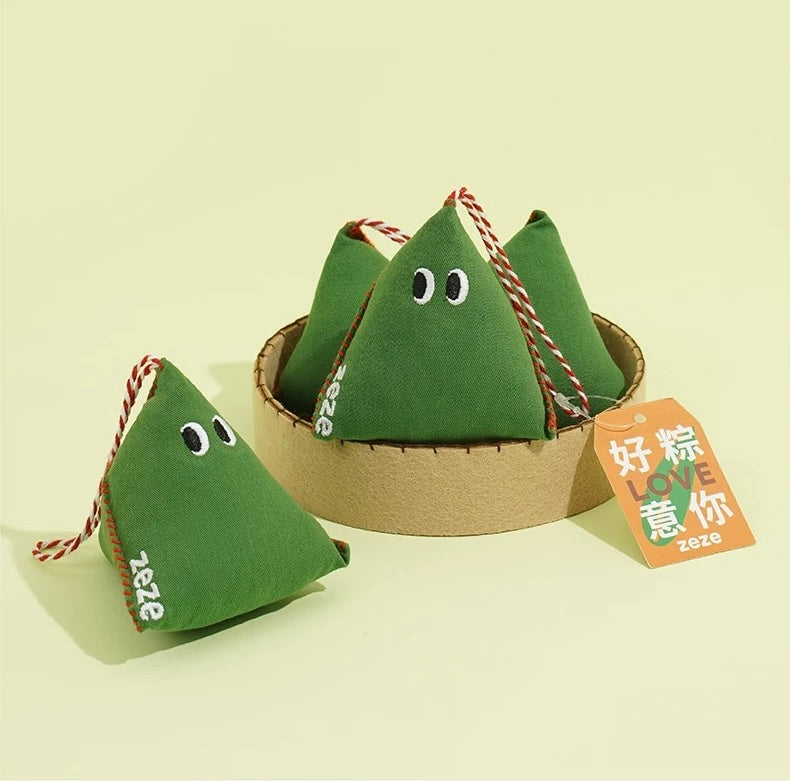 Green triangular cat toy with a face and red string, featuring a type of Chinese Dumpling - 粽子